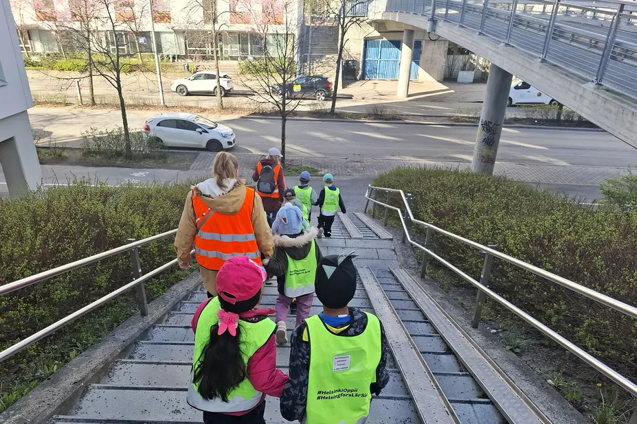 Lapsia ja aikuisia parijonossa kaupungilla.