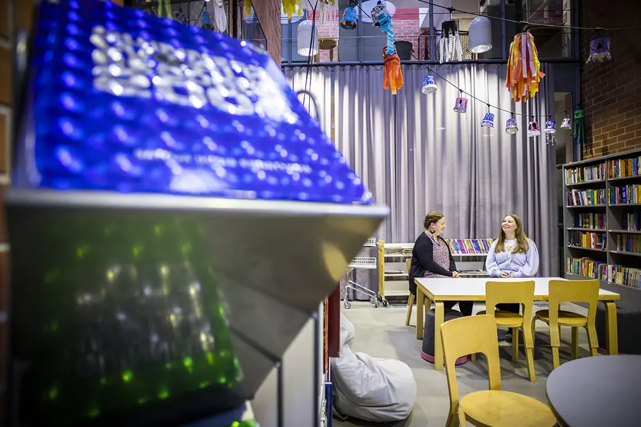 Alkula ja Pelgonen istuvat ja juttelevat koulun kirjastossa