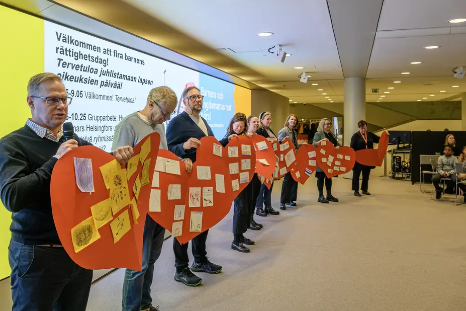 Kaupungin edustajat seisovat käsissään paperit, joihin on koottu lasten näkemykset.