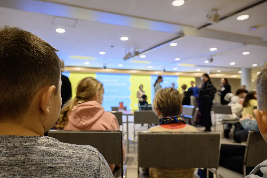 Lapsiyleisöä kuvattuna takaapäin.