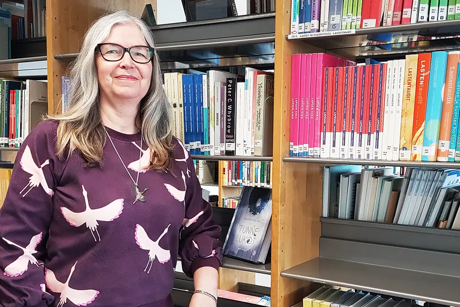 Tuija Takala kirjahyllyn edessä