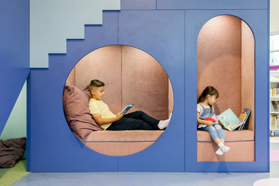 Two children reading in the reading nooks of Pikku Huopalahti Library.