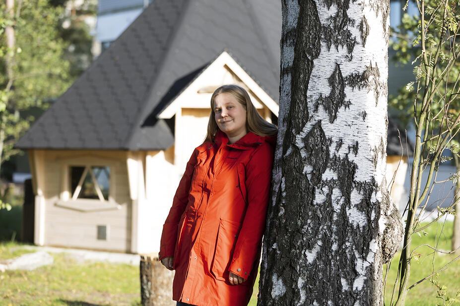 Heidi Kuvaja nojaa puunrunkoon ulkona