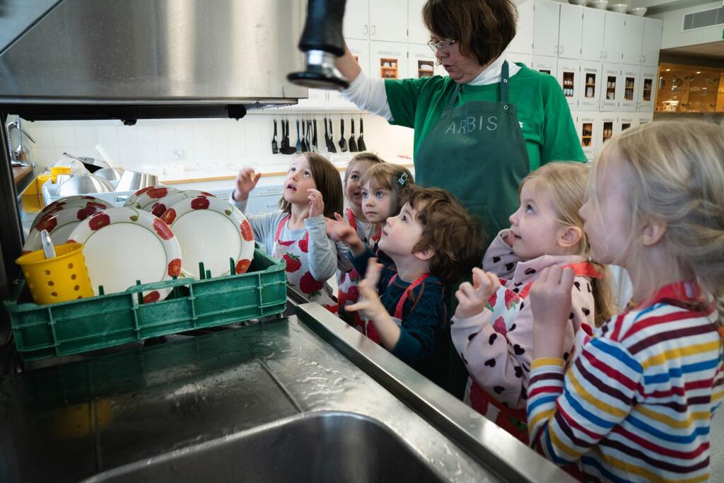 Barnen från Daghemmet Pilten hjälper Ghita Henriksson att diska i Arbis undervisningskök. Bild: Tuomas Hakkarainen