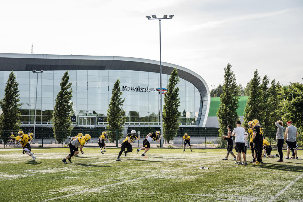 En grupp idrottare spelar amerikansk fotboll på en gräsplan.