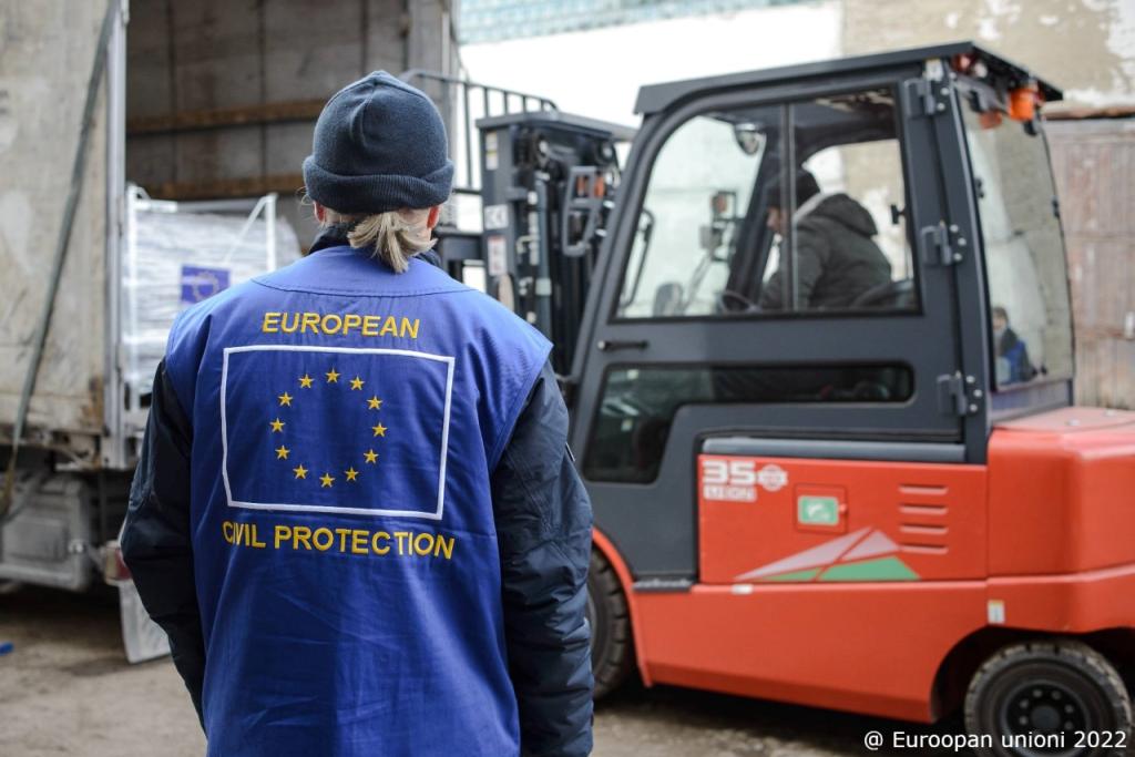 Trukilla nostetaan tavaraa rekkaan. Miehen selässä on EU:n lippu ja lukee European Civil Protection.