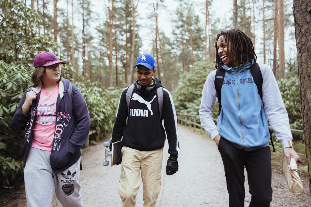 Троє молодих людей прогулюються парком після навчання.
