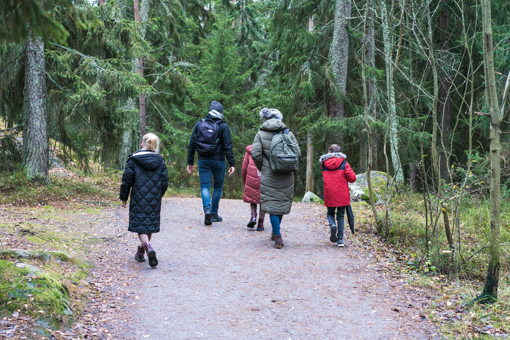 Perhe kävelemässä metsätiellä