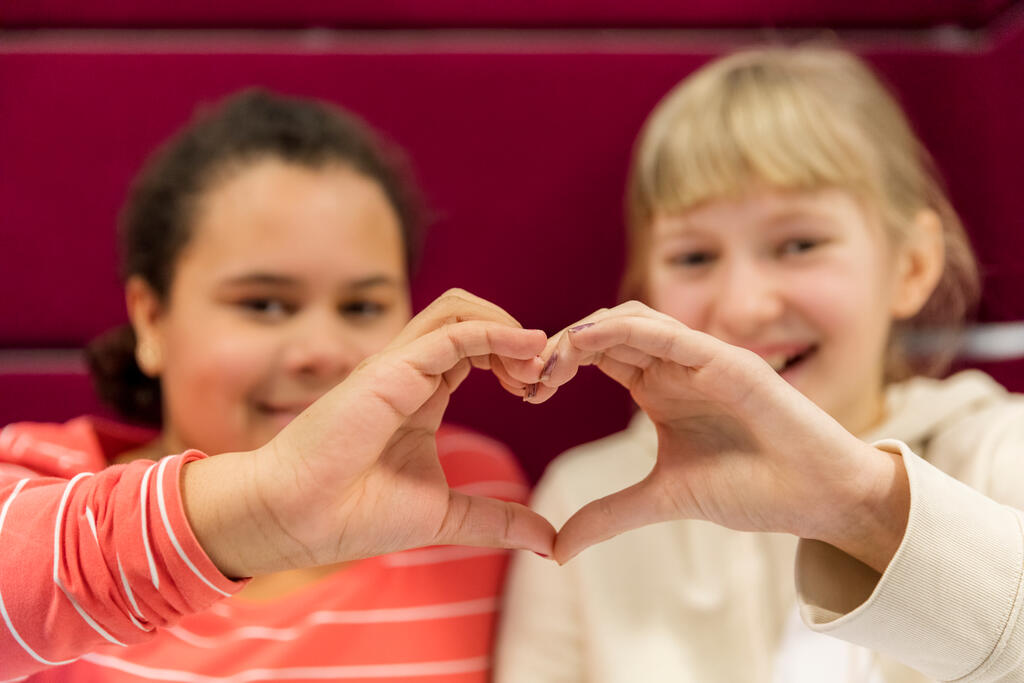 Two children form a heart with their hands.
