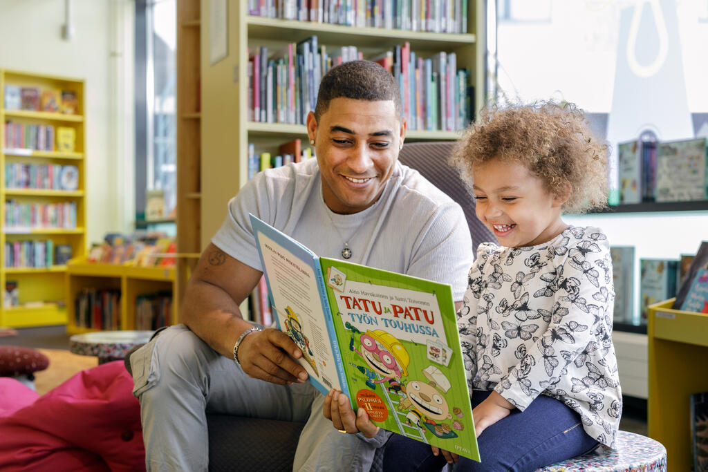  En vuxen och ett barn läser en bok.