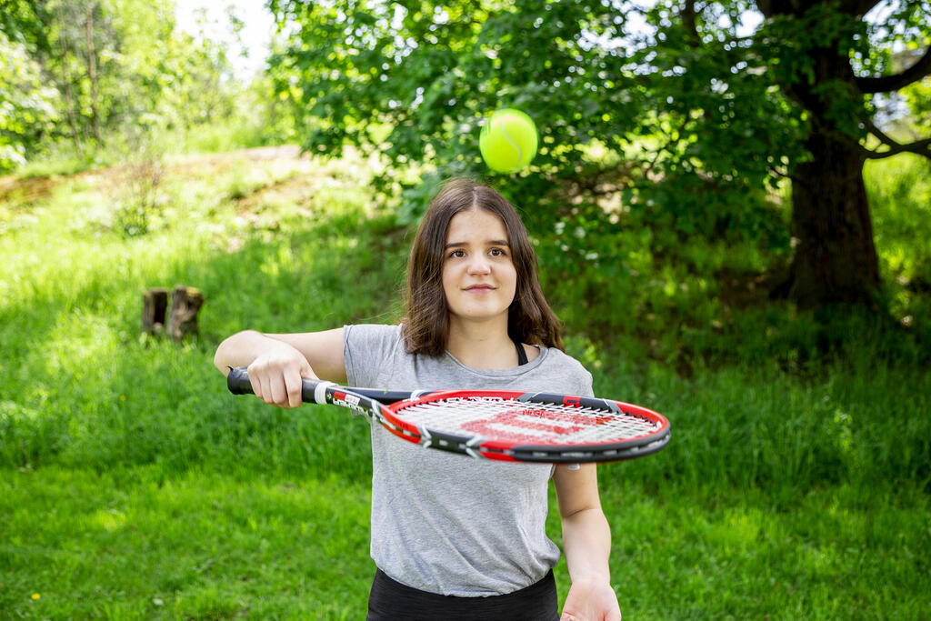 Tyttö pomputtelee mailalla tennispalloa.