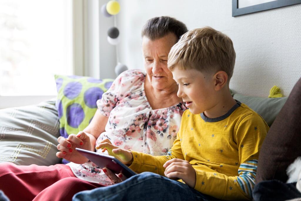 A grandmother and child reading an e-book on a tablet computer.