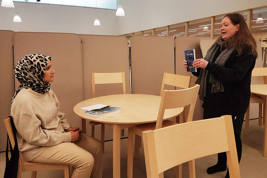 Heidi Naukkarinen esittelee Shadan Ali Salihille selkokirjaa ja kertoo, että sellaisia voi lainata kirjastosta.