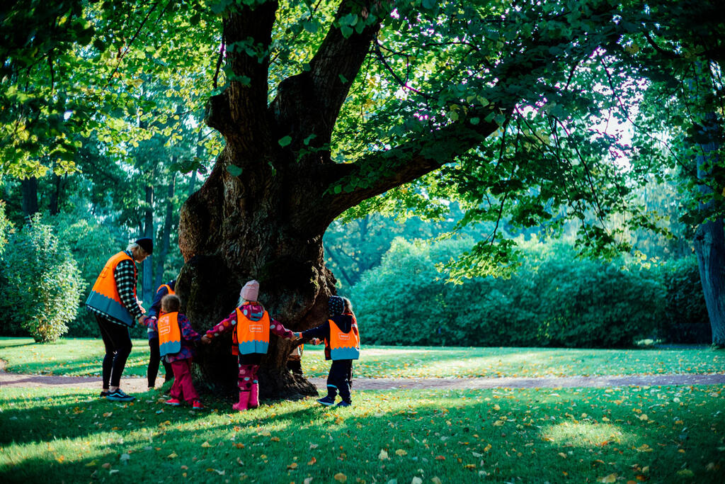Lapsia leikkimässä puun ympärillä.