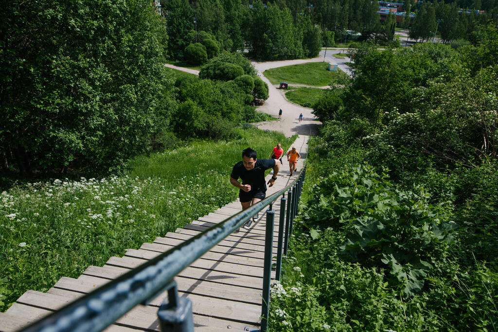 Троє спортсменів біжать угору по сходах для фітнесу в Малмінкартано (Malminkartanon kuntoportaat).