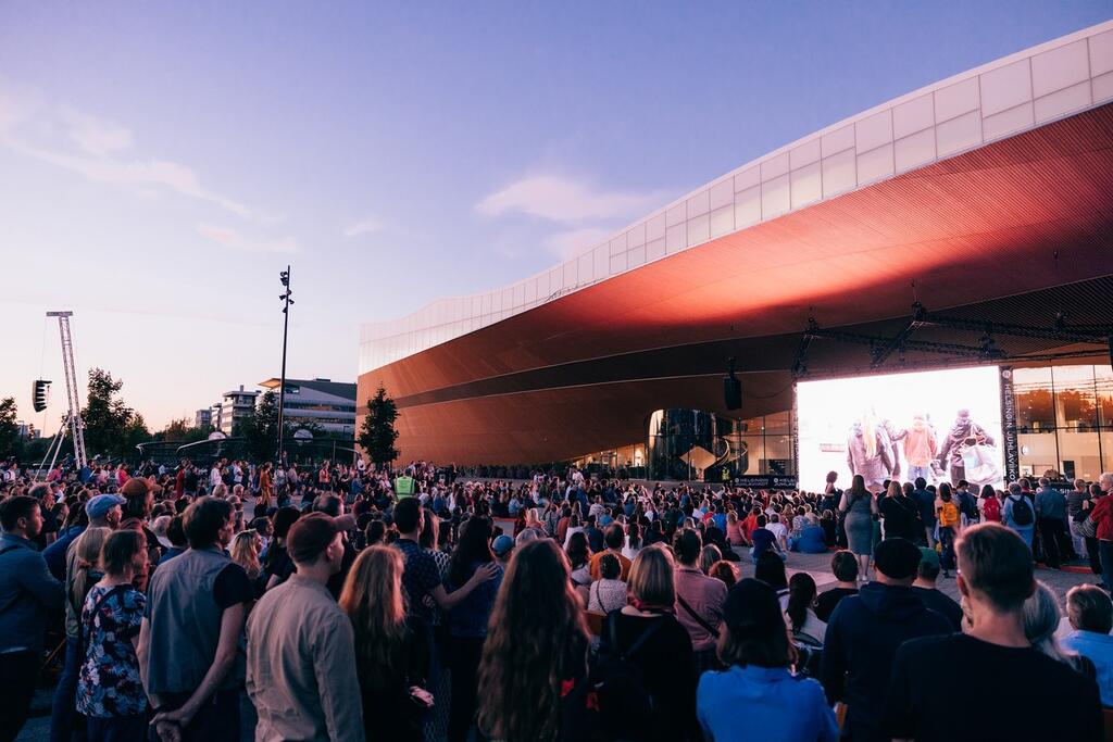 People in front of Central Library Oodi at dusk.