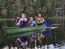 Kolme ihmistä soutaa kanootilla järvellä