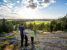 Mies ja poika katselevat Hallainvuoren kallioilta Viikin peltojen yli länteen.