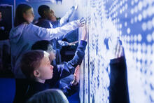 Oppilaat kokeilevat interaktiivista seinää kokeilukontissa.