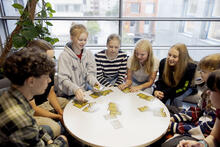 Oppilaita pyöreän pöydän ympärillä katsomassa sanakortteja