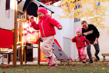 Kaksi lasta juoksee leikkipuiston pihalla syksyllä