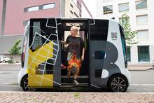 Matkustaja nousemassa ulos robottibussista. Taiteilijoina Laura Beloff & työryhmä: R-Bus, 2023 