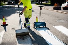 Staran työntekijä maalaa suojatietä asfalttiin.