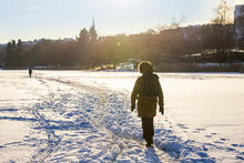 Ihminen kävelemässä Töölönlahden jäällä aurinkoisessa talvisäässä.