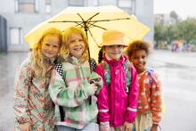 Lapsia kuvassa sateenvarjon alla