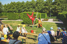 Punaiseen asuun pukeutunut henkilö taiteilee vehreässä puistossa