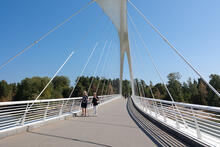 Kaksi henkilöä kävelee sillalla.
