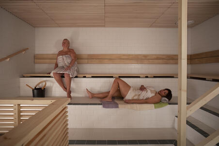  Yrjönkadun uimahallin sähkösauna. Kaksi ihmistä saunomassa pyyhkeet ympärillään.