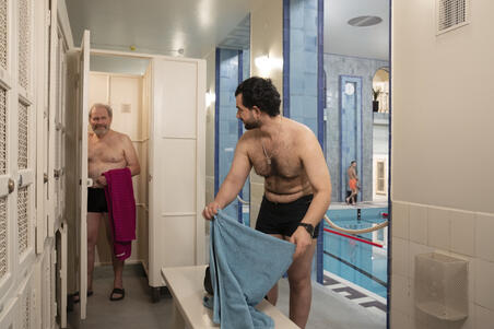  Kaksi uimaria Yrjönkadun uimahallin ensimmäisen kerroksen käytävällä pukukaapeilla.