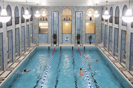  Kolme ihmistä ui Yrjönkadun uimahallin isossa uima-altaassa.