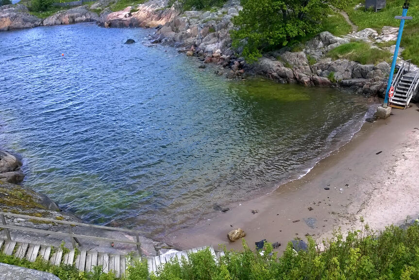 Pieni hiekkaranta poukamassa, jonne johtavat jyrkät portaat.