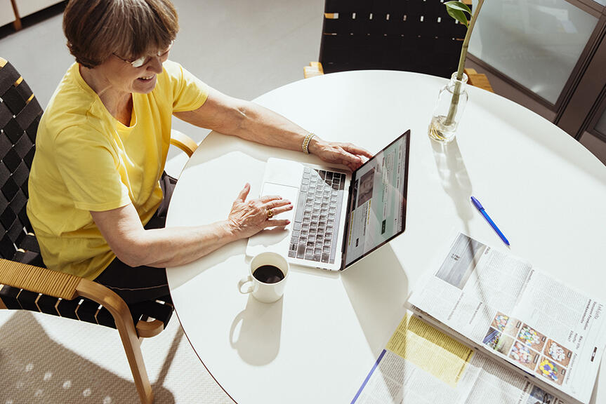 A woman is sitting at a table and using a computer.