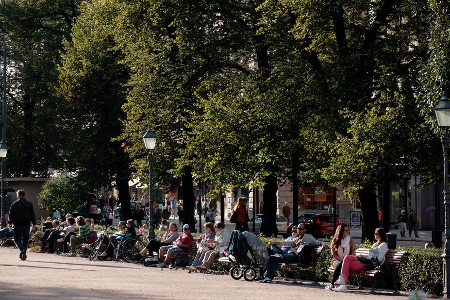 Ihmisiä Esplanadinpuiston penkillä kesäpäivänä.
