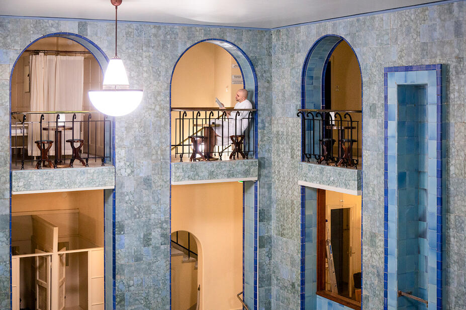 Parvikerros ja kaariholvia, henkilö istuu kylpytakissa.