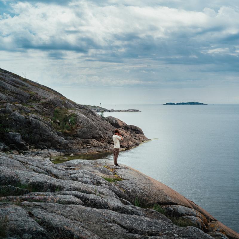 Mies seisoo rantakalliolla Helsingin Vallisaaressa.