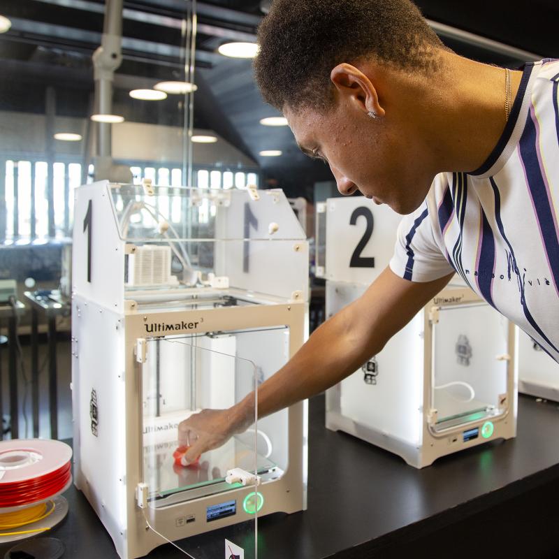 A young man uses a 3D printer in the Oodi library