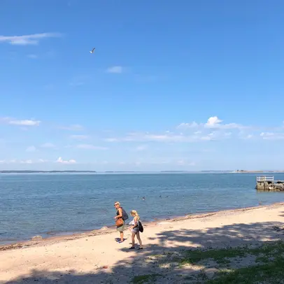 Henkilöt kulkevat hiekkarannalla.