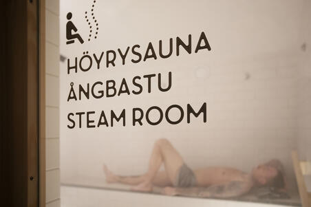  Yrjönkadun uimahallin höyrysaunan oven läpi näkyy lauteilla makoileva ihminen.