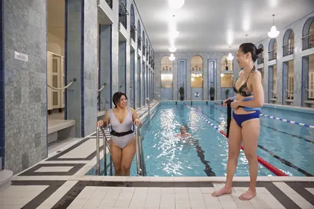 Personer med aquajoggingbälten som står vid poolkanten.