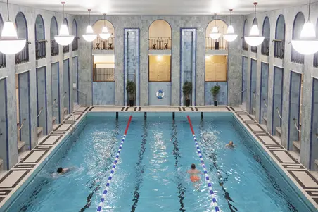 Tre personer simmar i den stora bassängen i Yrjönkatu simhall.