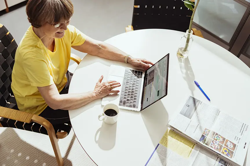A woman is sitting at a table and using a computer.