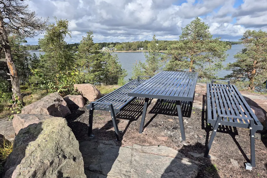 Pöytäryhmä kalliolla merimaiseman äärellä.