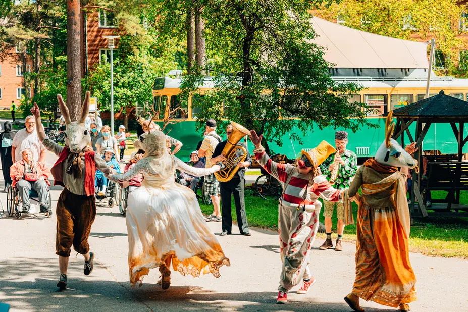 The picture depicts a theatre carnival group Fauna Humana on Helsinki Day, wearing colorful costumes on a sunny summer day. 
