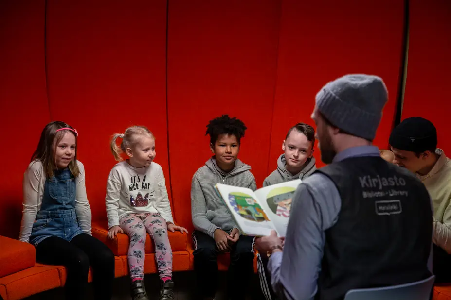The librarian is reading a book to the children.