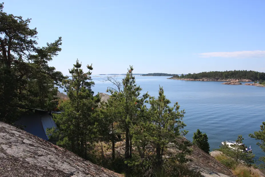 Näkymä kalliolta merelle, jossa lipuu alus.