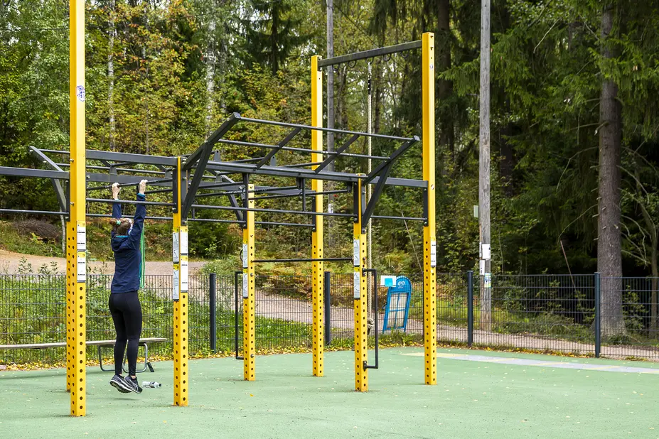 Henkilö Pirkkolan ulkokuntosalin monitoimilaitteessa.